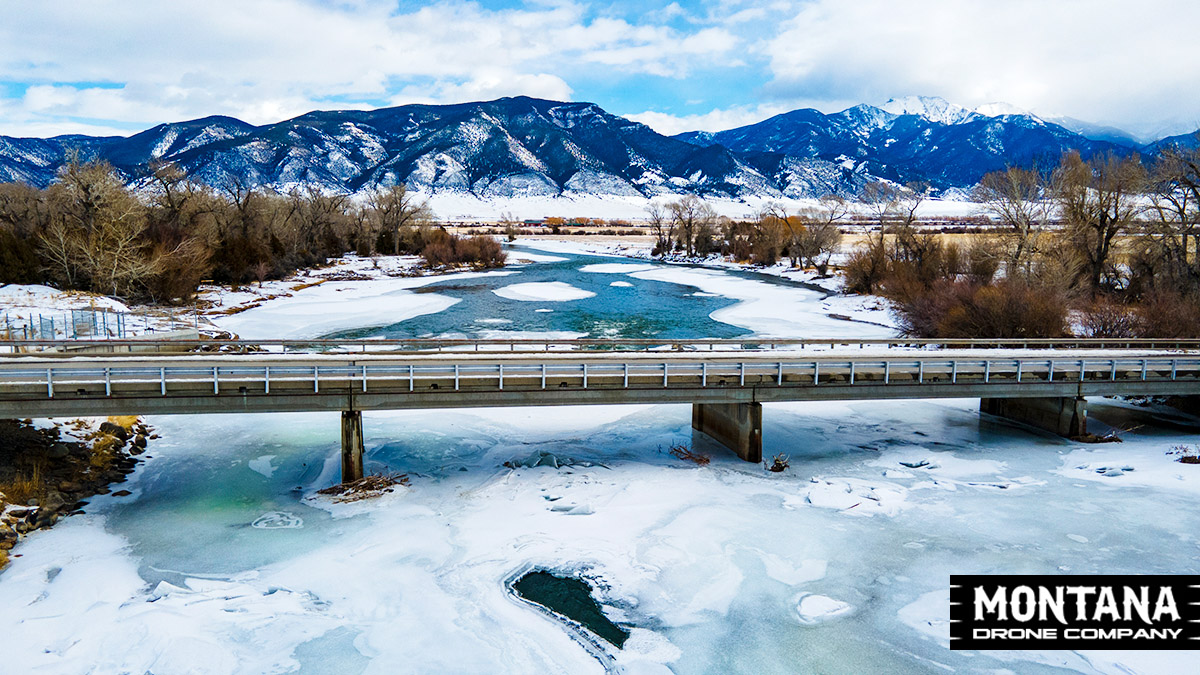 Highway Bridge Over Frozen River Montana Mountains Backdrop